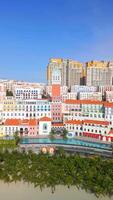 Aerial view of Sunset Town in Phu Quoc, Vietnam, showcasing pastel-colored European-style buildings, beach, and palm trees under a clear blue sky. video