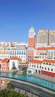 Aerial view of Sunset Town in Phu Quoc, Vietnam, showcasing pastel-colored European-style buildings, beach, and palm trees under a clear blue sky. video