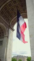 French flag beneath Arc de Triomphe with cloudy sky in Paris, France 06.08.2025 video