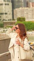 Woman with coffee adjusting sunglasses in business area video