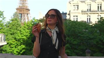 Woman enjoying croissant near Eiffel Tower in Paris video