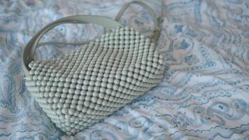 Stylish beaded handbag on patterned fabric backdrop video