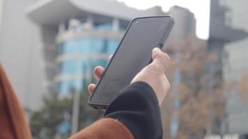 Individual with smartphone, modern architecture behind video