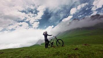Young man getting on his bike in the mountains. Aerial view from fpv drone. Start of mtb downhill cycling rider video