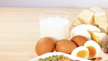Variety of protein-rich foods including nuts, eggs, and dairy are artfully arranged on a wooden table video