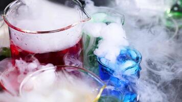 Vibrant liquid reacting with smoke in beakers video