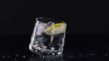 Glass tilts, lime slice inside, black background video