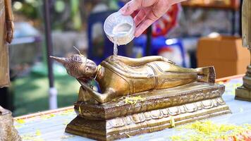 Sequential water pouring on a reclining Buddha statue video