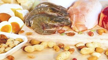 A vibrant display of various protein-rich foods including nuts, seafood, and dairy, arranged on a wooden surface with bright lighting video