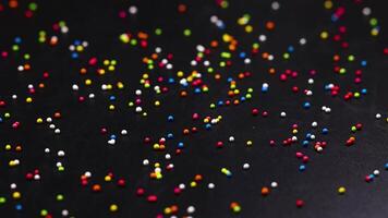 Multicolored sprinkles scattered on a dark background video