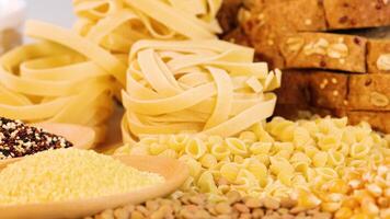 A variety of grains, pasta, and bread are displayed on a blue backdrop, highlighting texture and color contrast video