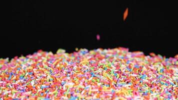 Rainbow sprinkles cascade onto a black background video