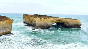 Dynamic ocean waves crash against rugged cliffs at Port Campbell, Australia. Captured in natural daylight with vibrant blues and greens video