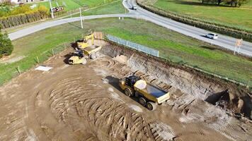 Drone footage captures an excavator and dump truck working on a construction site under bright daylight in Cromwell, New Zealand video