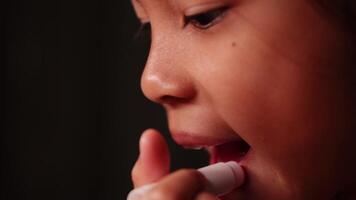 Close-up of cute little Asian girl's face applying lipstick in front of mirror. video