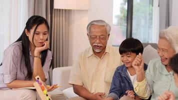 A family enjoys a lively dice game in a bright, cozy living room, fostering joy and connection across generations video