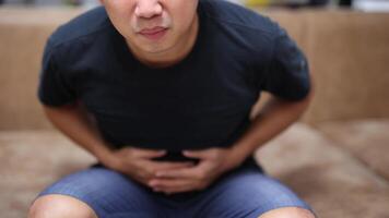 Man sit on sofa feel stomachache touch his belly in the room video