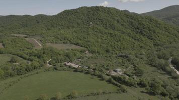 aerial view fly over green caucasus mountains over property and historical ruins on hillside video