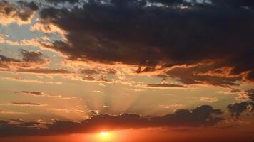Bright golden sunbeams shining through purple clouds moving up. Red orange cloudscape of sunset time lapse. Dark dramatic sky while sundown in dusk video