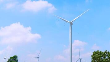 a wind turbine stands tall under a bright blue sky with white clouds. The wind turbine symbolizes clean energy and sustainability. Ideal for topics related to renewable energy, wind turbine technology video