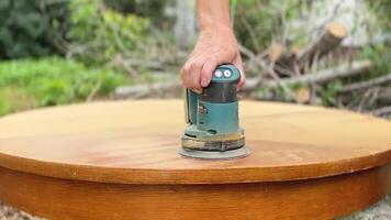 A man, worker uses a grinder. Grinder grinds wooden furniture. Close up video