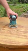A man, worker uses a grinder. Grinder grinds wooden furniture. Close up vertical footage video
