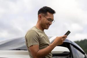Digital Connection. Young man using smartphone outdoors near car. photo