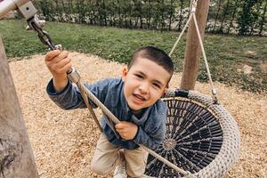 A child climbs up an alpine grid in park on a playground on a hot summer day. children's playground in a public park, entertainment and recreation for children, mountaineering training. photo