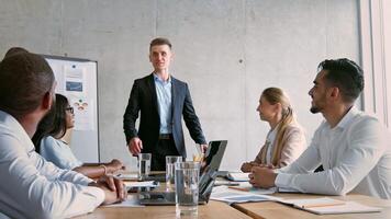 A group of professionals engage in a productive meeting in a contemporary office. A presenter conveys ideas while colleagues actively participate, showcasing collaboration in a dynamic workspace. video
