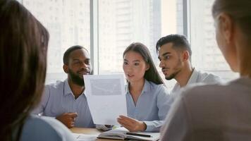 A diverse group of professionals gathers in a contemporary office, engaging in a productive discussion about project strategies. They review documents while brainstorming ideas for success. video