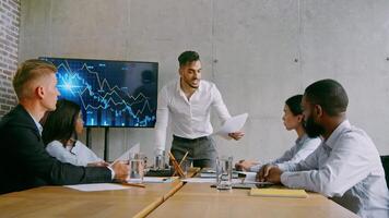 A diverse group of professionals engages in a strategy meeting in a contemporary office. One member presents data charts, while others take notes and discuss business objectives. video
