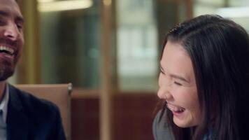Happy laughing multiethnic business coworkers discussing windmill ecology project green energy wind turbine model Korean businesswoman Caucasian businessman environment laugh investment deal at office video