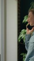 Happy Caucasian woman talking mobile phone looking window waving hand hi at home smiling business female girl businesswoman speaking cellphone call delivery order chatting greeting wave arm gesturing video