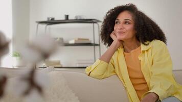 Dreamy African American ethnic calm woman dreaming on couch cozy sofa leisure relaxed girl home owner enjoy comfort fresh air rest at own rented apartment thinking smiling imagine future plans dreams video