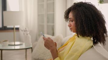 African American young woman ethnic pretty girl media scrolling on phone modern smartphone smiling female read email play mobile game browsing internet store online shopping texting messages side view video