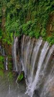 Cinematic FPV drone shot diving through the stunning multi-stream Tumpak Sewu waterfall, surrounded by lush rainforest cliffs in East Java, Indonesia. video