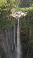 Aerial view of majestic Tumpak Sewu waterfall cascading into deep jungle canyon surrounded by lush rainforest in East Java, Indonesia. video