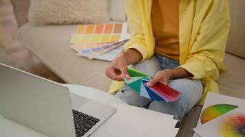 Unknown woman hands hold colors palette guide graphic designer architect girl choosing sample of material color tone select multicolor shades for house design project on laptop hold colorful swatches video