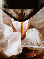coffee being poured into a glass with ice cubes photo