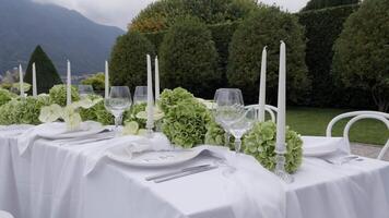 An Elegant Outdoor Dining Setup Featuring Beautiful Greenery and Soft Candlelight. Action video