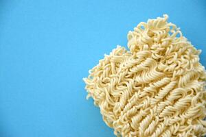 Raw instant noodles on blue paper background photo