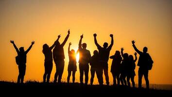 Silhouetted Group of Young Adults Celebrating Victory on Mountain Peak at Golden Sunset Symbol of Unity Ambition photo