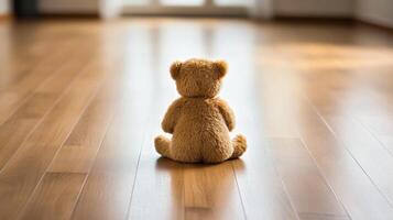 Soft teddy bear sitting alone on wooden floor in bright room during afternoon sunlight photo