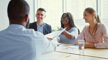 Professionals engage in a collaborative discussion in a bright office. They exchange documents while sharing ideas. The atmosphere reflects focus and determination among the team members. video