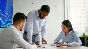Three professionals engage in a discussion in a modern office. They analyze documents and graphs while strategizing for business growth and future projects. video