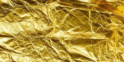 A close-up of a shiny, textured sheet of crumpled gold foil, perfect for backgrounds. photo