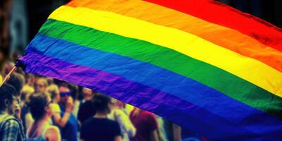 A rainbow pride flag waves with a crowd in the background, celebrating diversity and love. photo