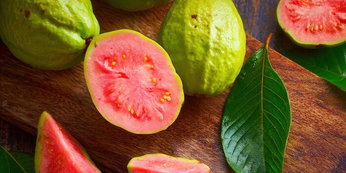 Delicious fresh guavas, both whole and sliced, arranged on a rustic wooden board. photo
