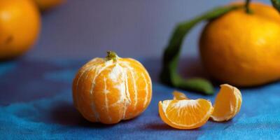 A vibrant close-up features a peeled mandarin orange and a segment on a blue surface. photo