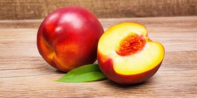 A beautiful shot of fresh nectarines, one cut open to reveal the tasty flesh and a single leaf. photo
